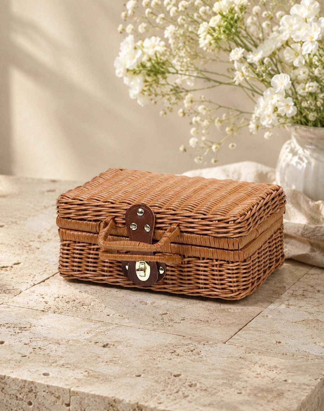 Wicker suitcase basket on a wooden surface with white flowers in the background