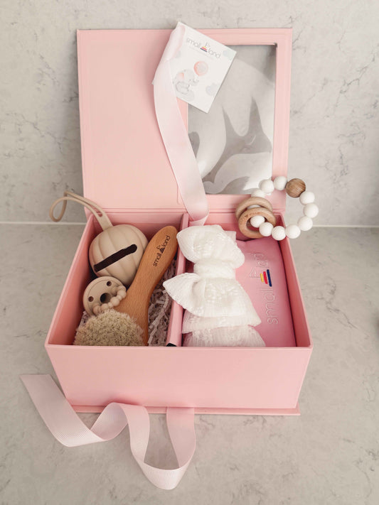 Pink gift box with baby care items on a light gray background