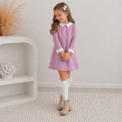 7 yr old girl in the Ariella winter dress paired with knee high white socks with cream ankle boots. She's posing and smiling, standing on white carpet.