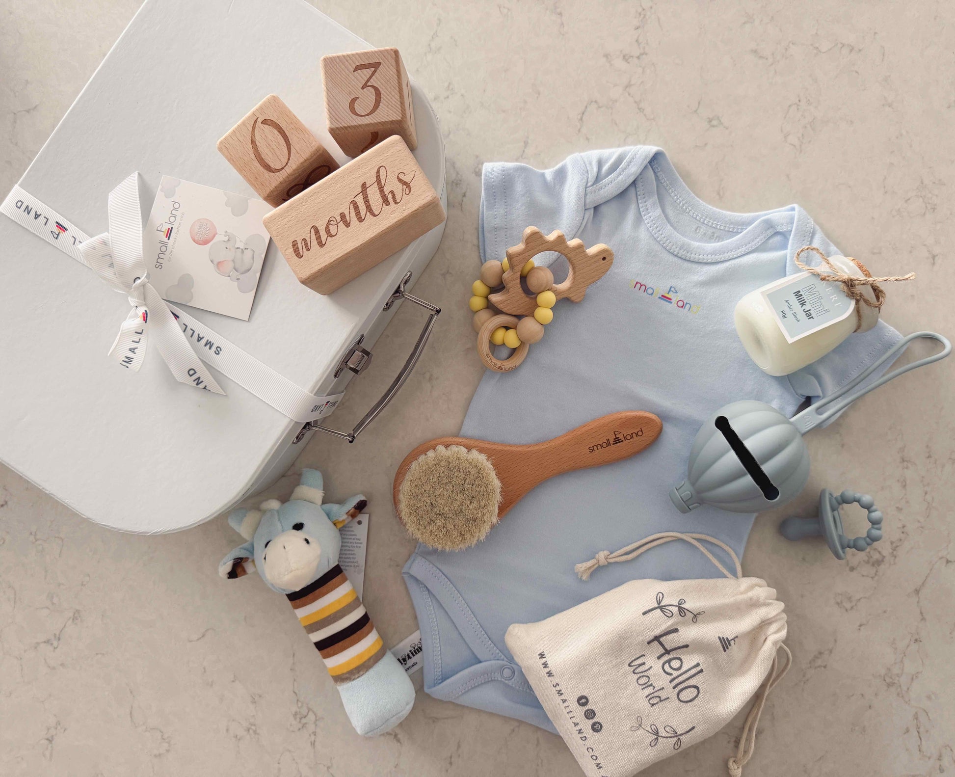 Baby clothing - onesie, baby toys  and suitcase gift box on a marbled surface