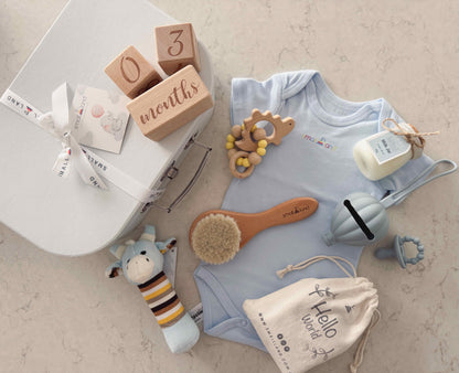 Baby clothing - onesie, baby toys  and suitcase gift box on a marbled surface