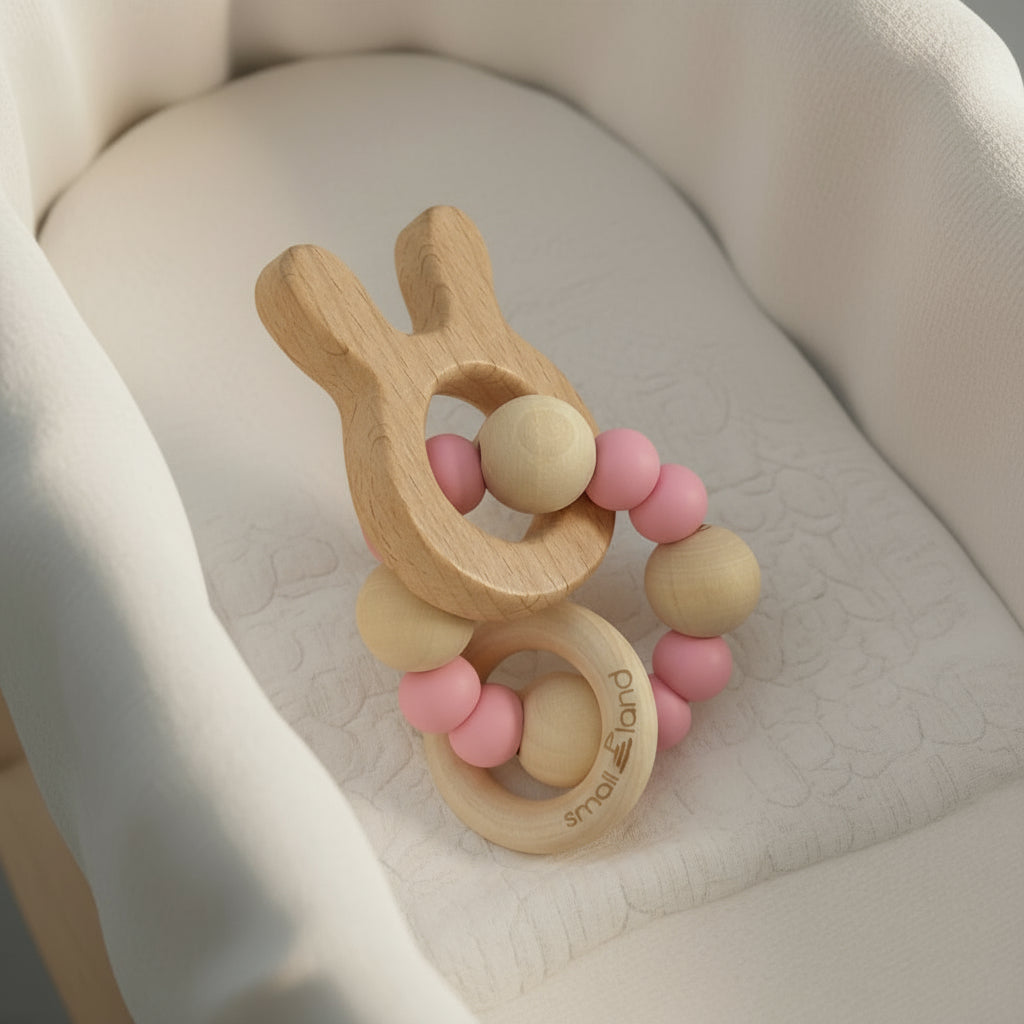 Wooden bunny teething ring with pink silicon beads on a soft beige surface