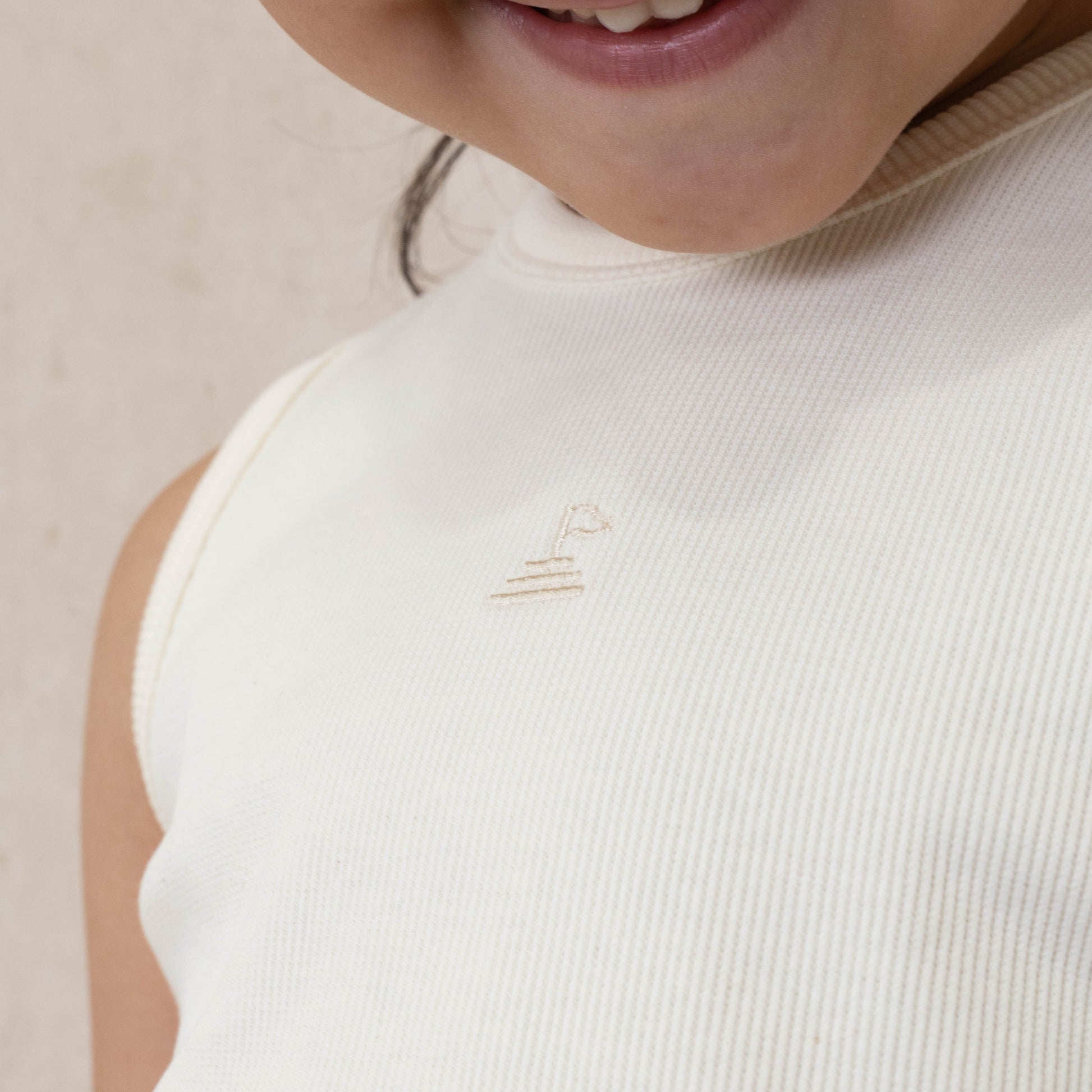 close up photo of cream ribbed set with logo embroidered at centre front