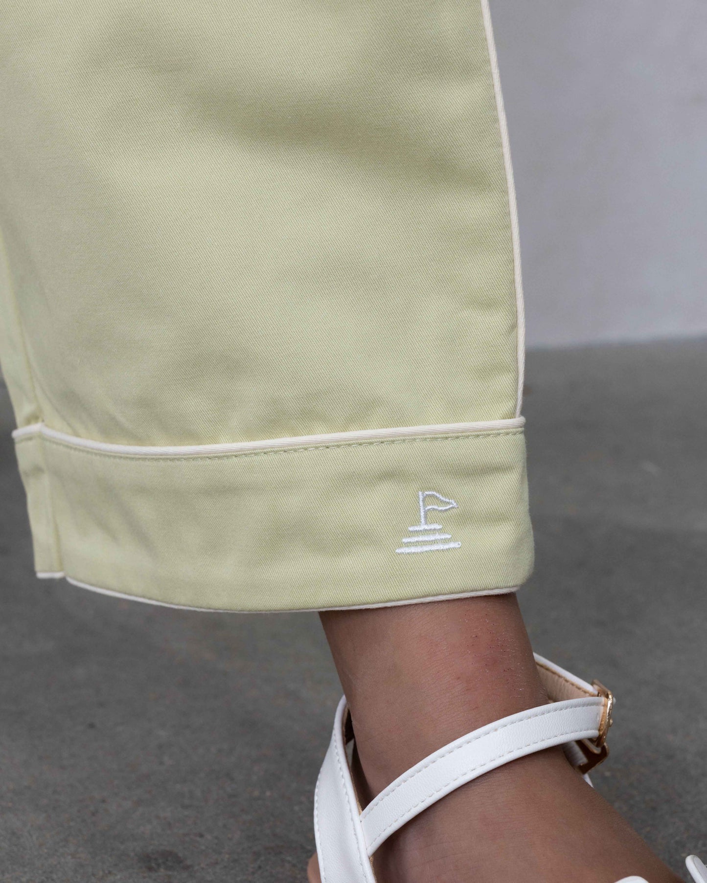 Close up detail of hem of pant, showing piping detail in white, and logo embroidery