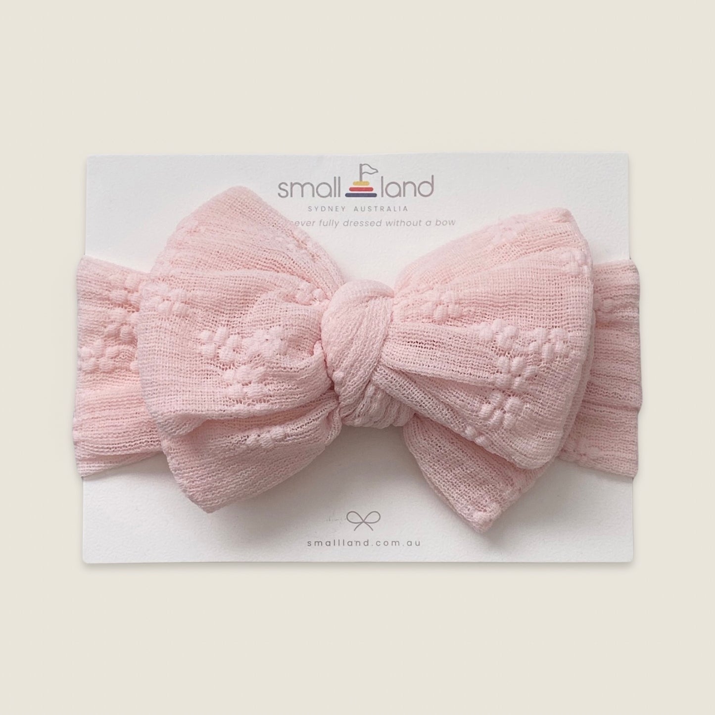 Flat lay image of girls pink lace headband in Small Land packaging 