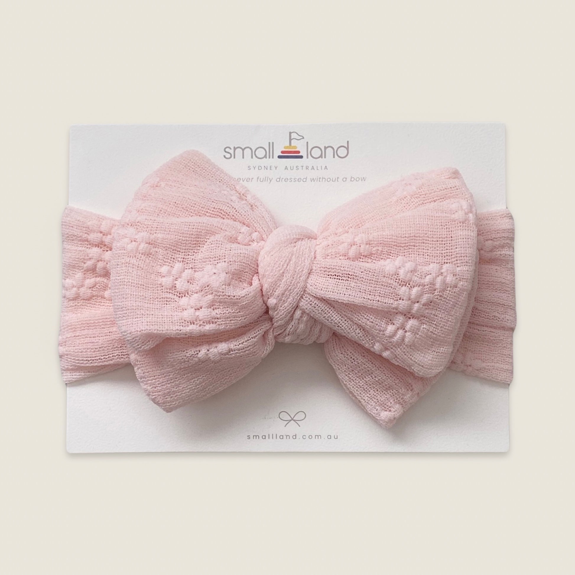 Flat lay image of girls pink lace headband in Small Land packaging 