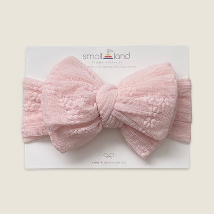 Flat lay image of girls pink lace headband in Small Land packaging 