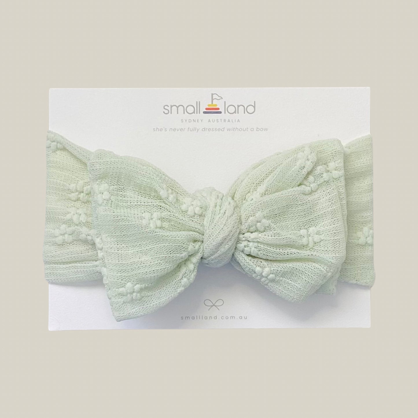 Flat lay image of girls sage lace headband in Small Land packaging 
