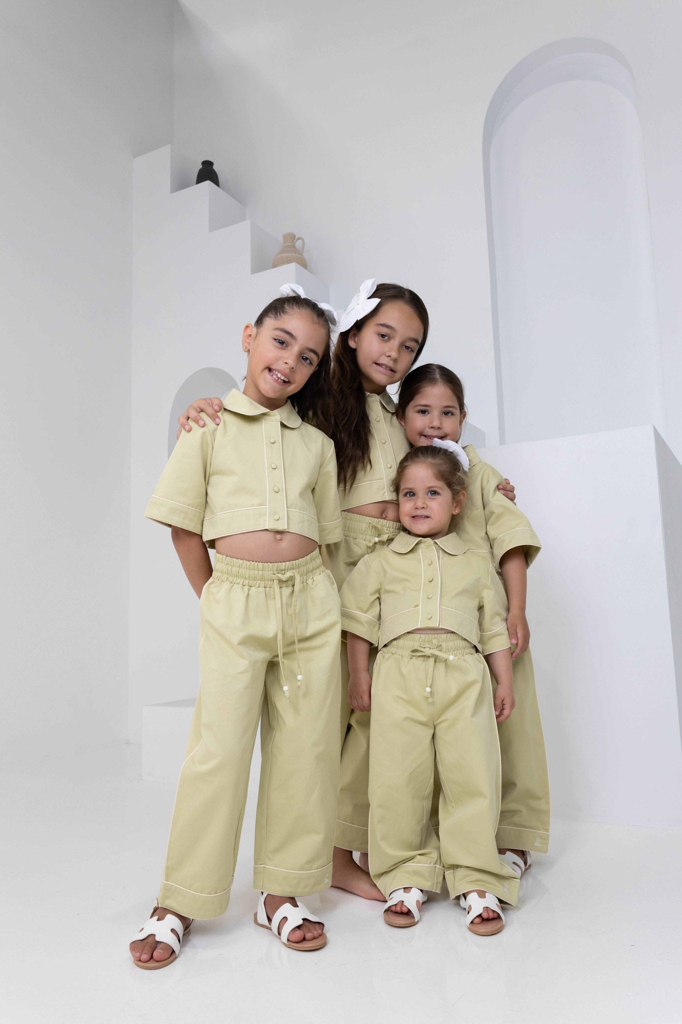 Four girl toddler models in different ages wearing our zara pant: high-waisted, relaxed-fit light shadow green pants with contrast white piping on side seams and an adjustable drawstring waist, paired with the matching Zara overshirt in the same colour. a trendy girls outfit